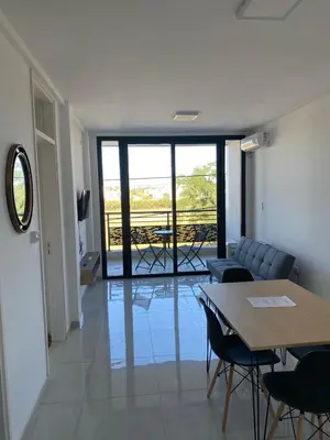 a living room with a table and chairs and a balcony at Dalcar Apart in Río Cuarto