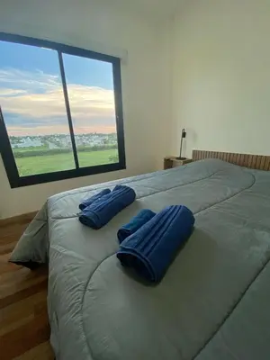 a large bed with two blue pillows on top of it at Dalcar Apart in Río Cuarto
