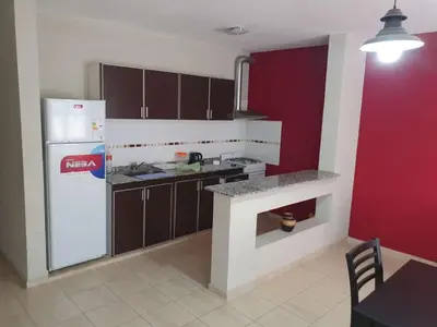 a kitchen with a white refrigerator and a red wall at HERMOSO DEPARTAMENTO EN QUINES in Quines