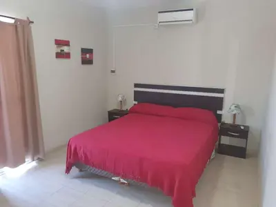 a bedroom with a bed with a red bedspread at HERMOSO DEPARTAMENTO EN QUINES in Quines