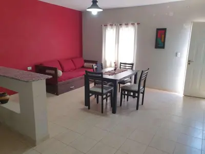 a living room with a table and chairs and a red couch at HERMOSO DEPARTAMENTO EN QUINES in Quines