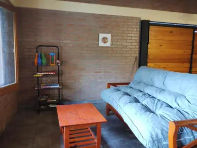 a living room with a blue couch and a brick wall at Alberobello Casa Serrana in Santa Rosa de Calamuchita
