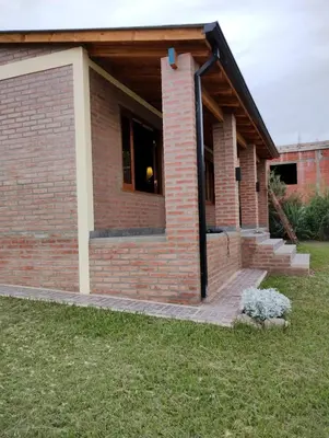 a brick house with a window and stairs in a yard at Alberobello Casa Serrana in Santa Rosa de Calamuchita