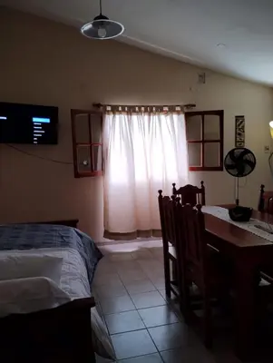 a bedroom with a bed and a table and a window at Alberobello Casa Serrana in Santa Rosa de Calamuchita