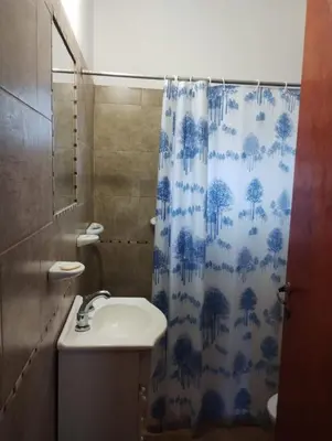 a bathroom with a blue shower curtain and a sink at Alberobello Casa Serrana in Santa Rosa de Calamuchita