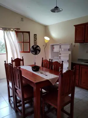 a kitchen with a wooden table with chairs and a refrigerator at Alberobello Casa Serrana in Santa Rosa de Calamuchita