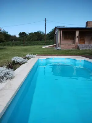 a blue swimming pool in front of a house at Alberobello Casa Serrana in Santa Rosa de Calamuchita