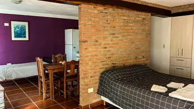 a bedroom with a brick wall and a bed and a table at Hospedaje Frente al Rio el Rancho in Santa Rosa de Calamuchita