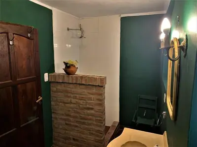 a bathroom with a toilet and a green wall at Hospedaje Frente al Rio el Rancho in Santa Rosa de Calamuchita