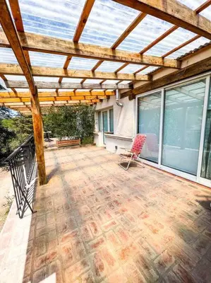 a patio with a wooden pergola and a chair at Hospedaje Frente al Rio el Rancho in Santa Rosa de Calamuchita
