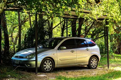 a small silver car parked under a canopy at Hospedaje Frente al Rio el Rancho in Santa Rosa de Calamuchita