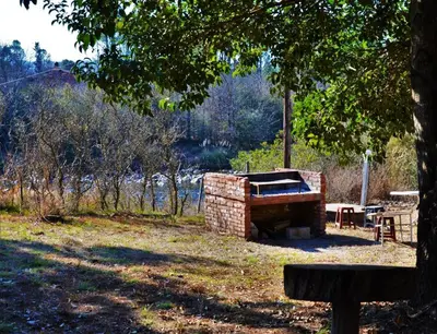 a brick fireplace in a park with a picnic table at Hospedaje Frente al Rio el Rancho in Santa Rosa de Calamuchita