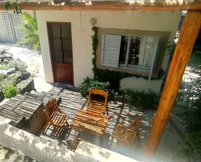 a group of chairs and a wooden bench in front of a house at Departamento San Antonio in San Antonio de Arredondo