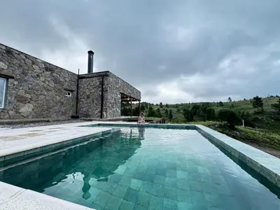 a woman sitting in a swimming pool next to a building at El Sauce in La Cumbrecita