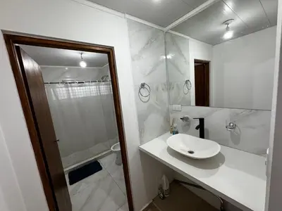 a white bathroom with a sink and a shower at El Sauce in La Cumbrecita