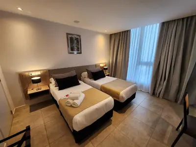 a hotel room with two beds and a large window at Amérian Río Cuarto in Río Cuarto