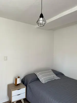 a white bedroom with a bed and a lamp at Departamento Pleno Centro de Córdoba Capital in Cordoba