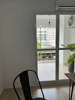 a black chair sitting in front of a sliding glass door at Departamento Pleno Centro de Córdoba Capital in Cordoba