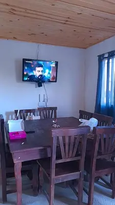 a wooden table with chairs and a television on a wall at Casa en Boca del Río in Las Tapias