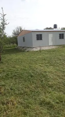 a white building in a field with a large yard at Casa en Boca del Río in Las Tapias