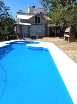a blue swimming pool in front of a house at Casa Villa Carlos Paz, con pileta, frente al río in Villa Carlos Paz