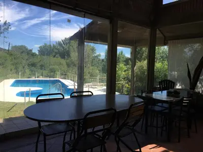 a dining room with a table and chairs and a pool at Casa Villa Carlos Paz, con pileta, frente al río in Villa Carlos Paz