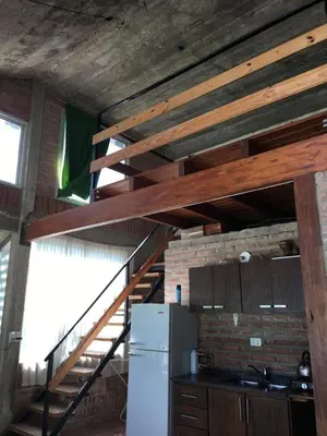 a kitchen with a staircase in a room with a refrigerator at Casa Villa Carlos Paz, con pileta, frente al río in Villa Carlos Paz