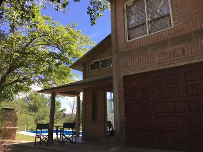 a house with a garage and a table and chairs at Casa Villa Carlos Paz, con pileta, frente al río in Villa Carlos Paz