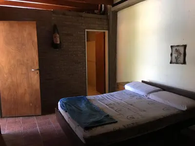 a bedroom with a bed and a wooden door at Casa Villa Carlos Paz, con pileta, frente al río in Villa Carlos Paz