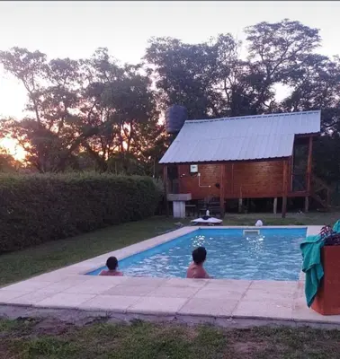 two people in a swimming pool next to a barn at Kapo TEAM , el zorzal in Villa Amancay