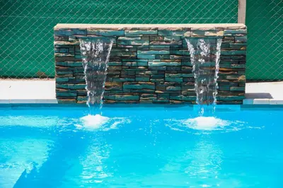 two water fountains in a pool with a stone wall at Village Vistello in Cordoba