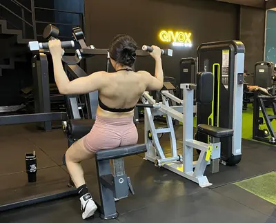 a woman is sitting on a bench in a gym at Village Vistello in Cordoba