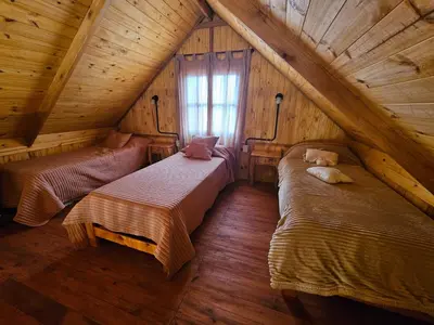 a attic room with two beds and a window at Cabañas en Los Reartes Córdoba in Villa General Belgrano