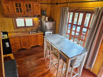 a kitchen with a table and chairs and a refrigerator at Cabañas en Los Reartes Córdoba in Villa General Belgrano