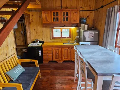 a kitchen with wooden cabinets and a table and chairs at Cabañas en Los Reartes Córdoba in Villa General Belgrano