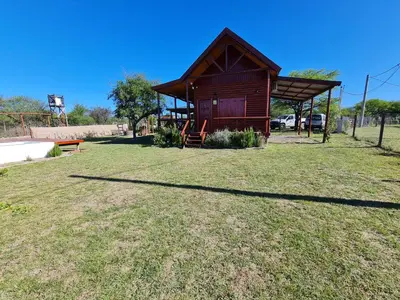 a small cabin in a field with a grass yard at Cabañas en Los Reartes Córdoba in Villa General Belgrano