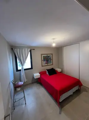 a bedroom with a red bed and a chair at Departamento equipado in Río Cuarto