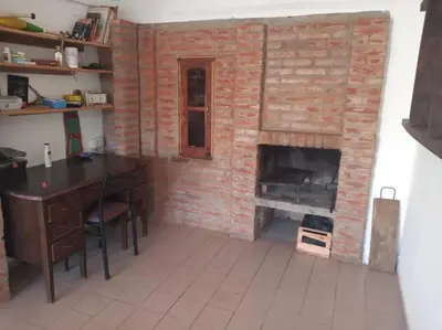 a room with a brick fireplace with a table and a desk at Colores de arguello in Cordoba