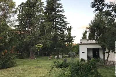 a small white building in a field with trees at Casa amplia en las sierras de San Luis in San Francisco del Monte de Oro