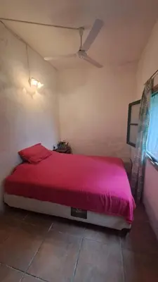 a bedroom with a red bed with a ceiling fan at Casa amplia en las sierras de San Luis in San Francisco del Monte de Oro