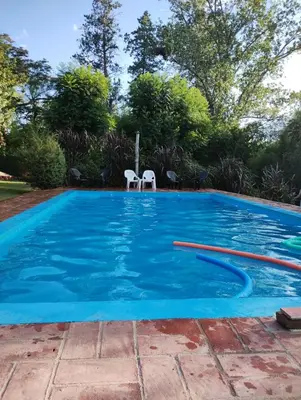 a swimming pool with two white chairs in it at Hospedaje FliaMaria in San Javier