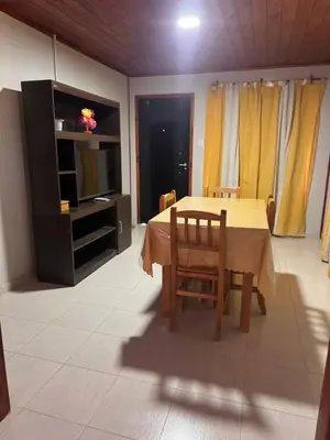 a dining room with a table and chairs and a television at Cabañas Adorable Tranquilidad in Cavalango