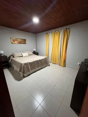 a bedroom with a bed and a window with yellow curtains at Cabañas Adorable Tranquilidad in Cavalango