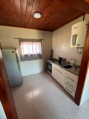 a small kitchen with a refrigerator and a stove at Cabañas Adorable Tranquilidad in Cavalango