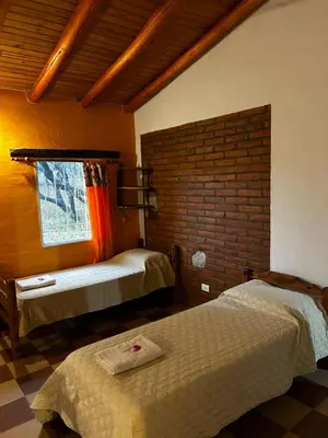 a bedroom with two beds and a brick wall at cabañas Villa de las rosas in Villa de Las Rosas