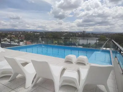 a swimming pool with white chairs on a balcony at Villa Carlos Paz departamento con pileta in Villa Carlos Paz
