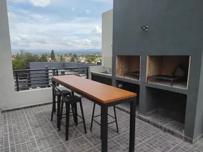 a table and chairs on a balcony with a fireplace at Villa Carlos Paz departamento con pileta in Villa Carlos Paz