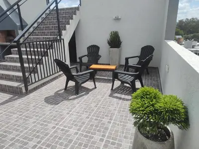 three chairs and a table on a patio with stairs at Dpto frente al Lago Carlos Paz in Villa Carlos Paz