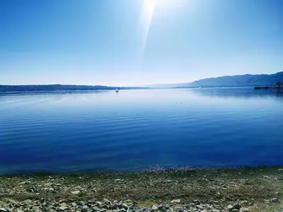 a large body of water with the sun shining at Dpto frente al Lago Carlos Paz in Villa Carlos Paz