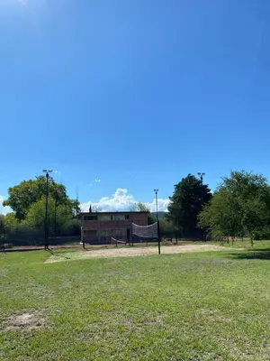 a building in a park with a volley ball court at Cabañas Ocho Soles in Las Rabonas